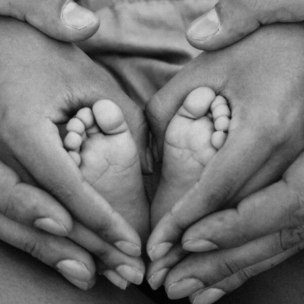 Grayscale Photo of Person Holding Feet and Hands