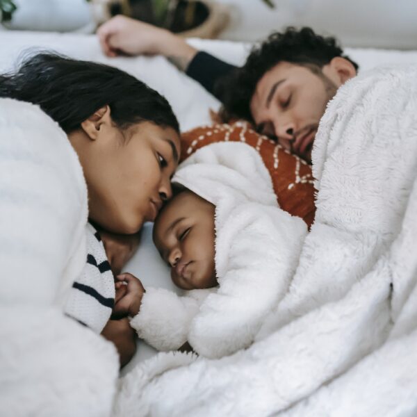 Calm ethnic family sleeping on bed in bedroom