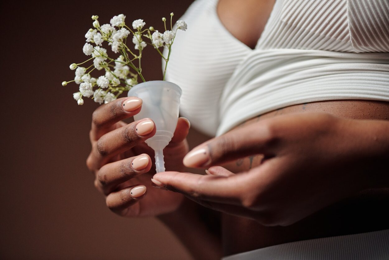 Person in White Underwear Holding a Menstrual Cup with Flowers