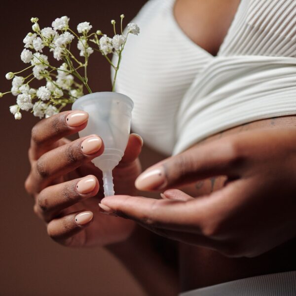 Person in White Underwear Holding a Menstrual Cup with Flowers
